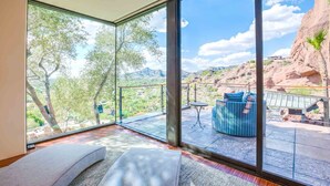 A room with large glass windows offering a view of a mountainous landscape.