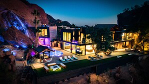 A modern house with a swimming pool, outdoor seating, and a waterfall feature.