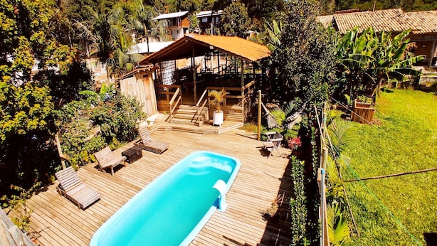 Un terrazzo in legno con piscina, lettini e una zona relax coperta.