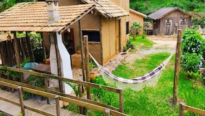 Una casa rustica con tetto in tegole, un'amaca e un pontile in legno.