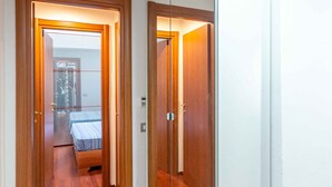 Un pasillo con suelo de madera que conduce a un dormitorio con cama y armario.