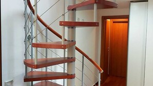 Una escalera caracol con escalones de madera y barandillas de metal.