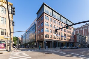 Un edificio de varios pisos con una mezcla de estilos arquitectónicos, incluyendo una esquina destacada con fachada de vidrio moderna y una sección tradicional de ladrillo.