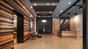 Un espace d’accueil moderne avec un mur revêtu de panneaux en bois, un comptoir d’accueil et un coin salon comprenant une table ronde et des chaises.