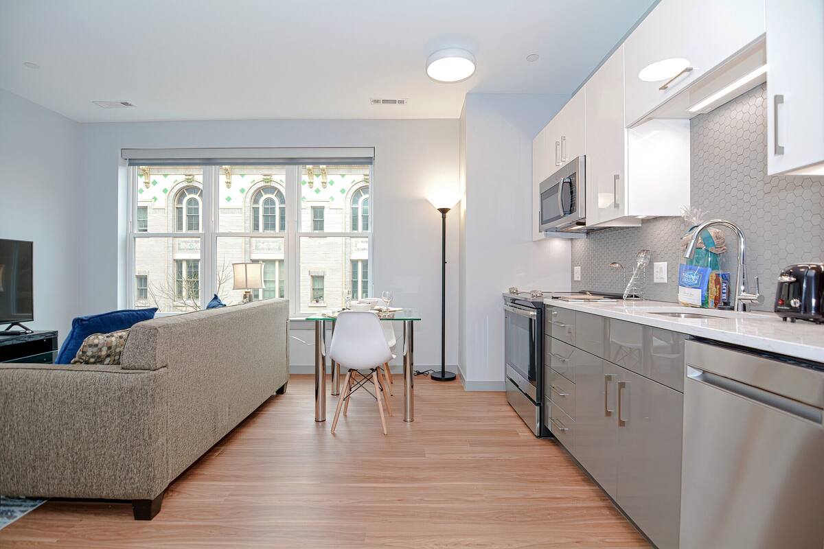 A modern apartment with a living room, dining area, and kitchen.