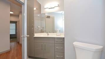 A modern bathroom with a large mirror, a white sink, and a toilet.