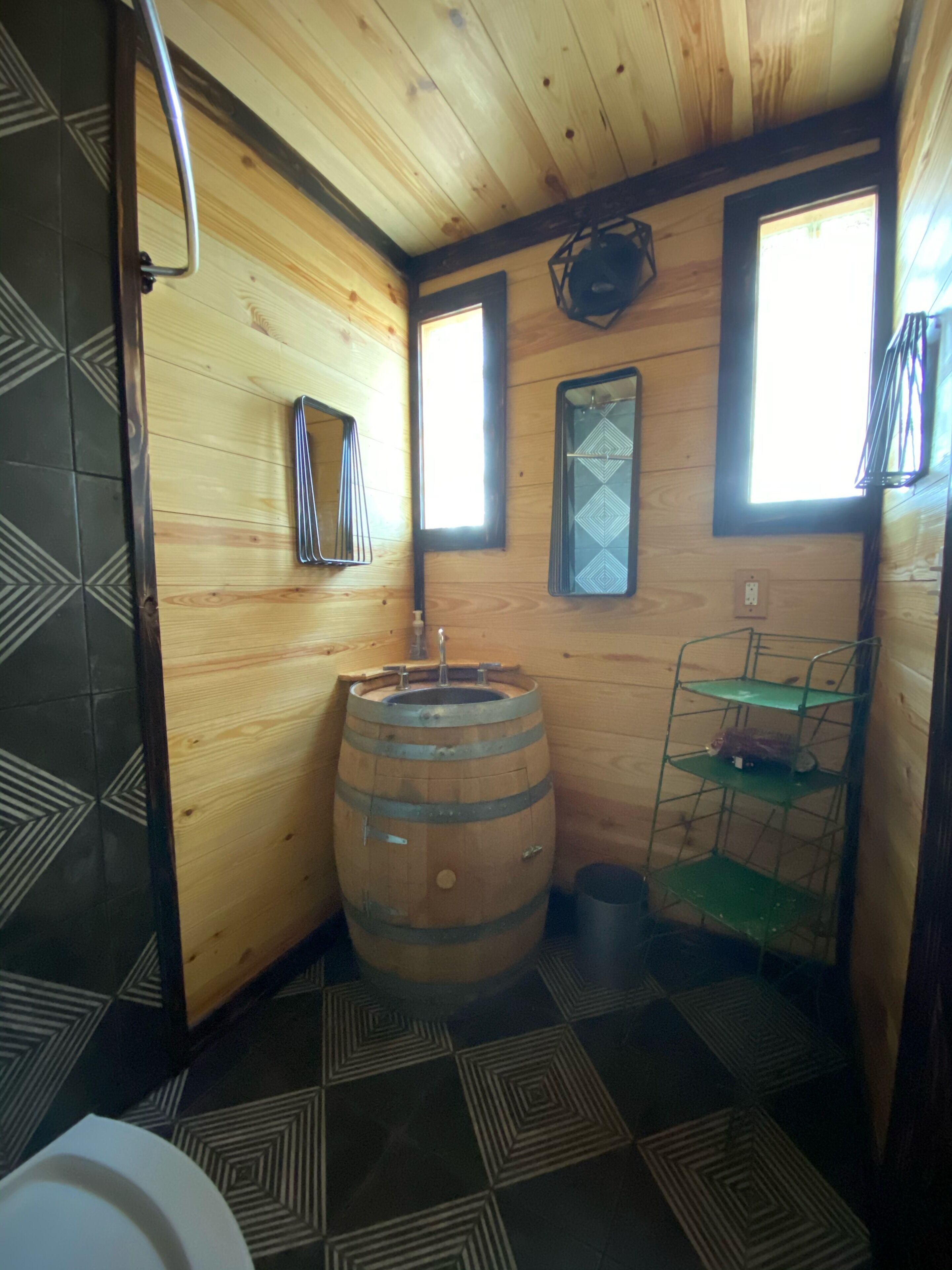 A wooden cabin interior with a wooden barrel, a metal shelf, and a window.