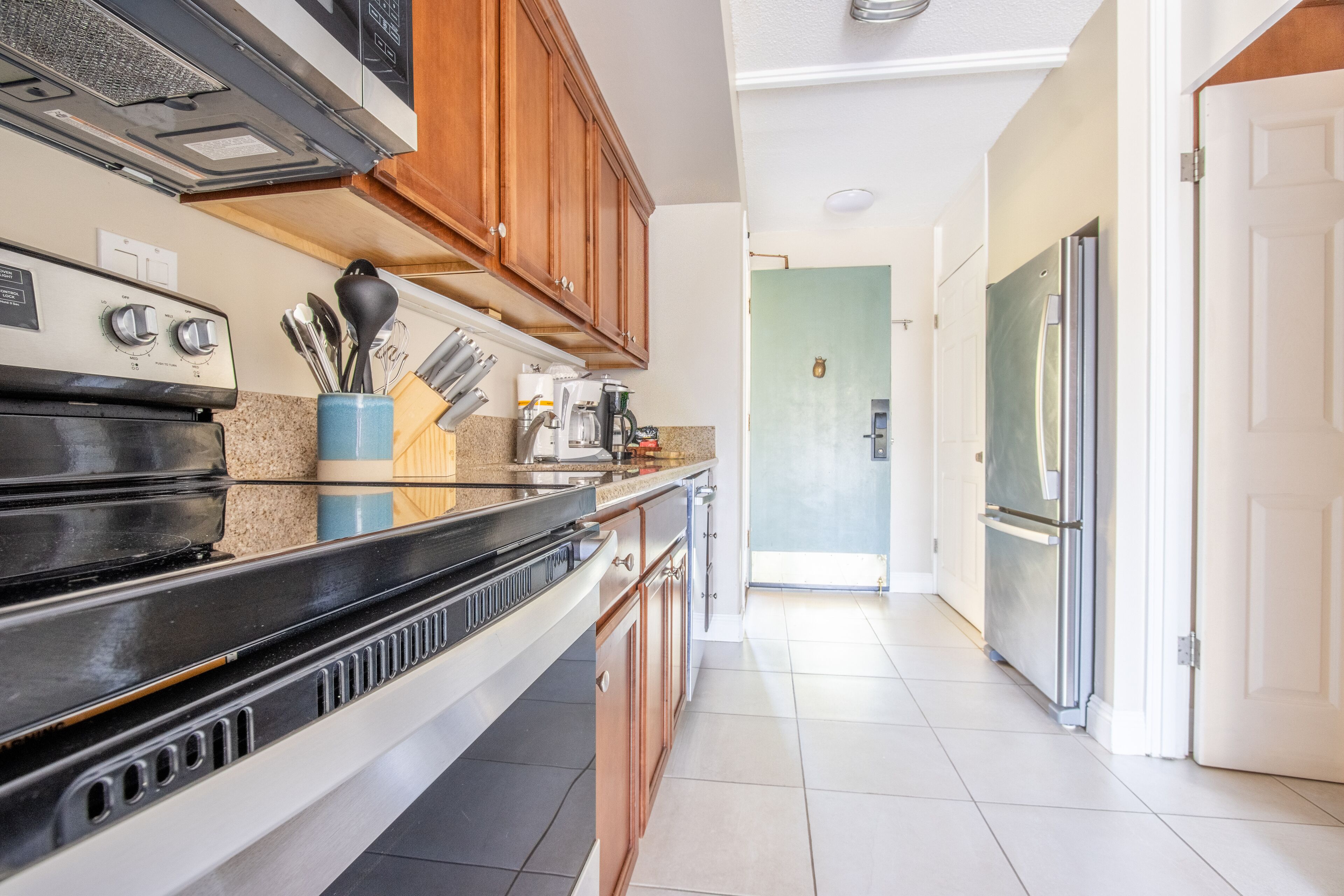 A modern kitchen with a stainless steel refrigerator, a built-in oven, and wooden cabinets.