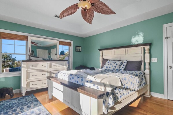 Un dormitorio con cama, cómoda y ventilador de techo.