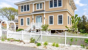A two-story house with a white picket fence, a front porch, and a small garden area. - Luney Dunes Penthouse (Newburyport)