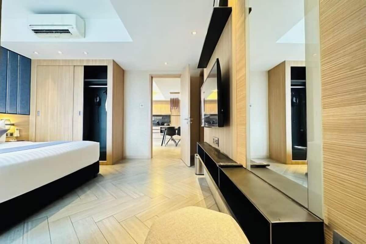 A modern hotel room with a bed, a TV, a desk, and a walk-in closet.