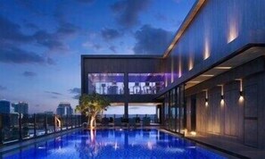 A modern building with a rooftop pool, large windows, and a view of the city skyline. - One Residence Hotel & Apartment (Phnom Penh)