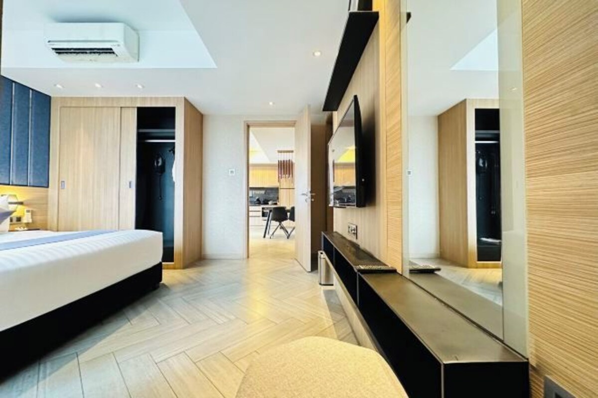 A modern hotel room with a bed, a TV, a desk, and a walk-in closet.