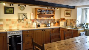 A kitchen with wooden cabinets, a stove, a sink, and a dining table. - Perfect for couples and familes to come and enjoy the local area. (Minehead)