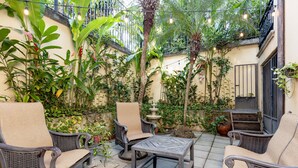 Une terrasse extérieure aménagée avec des meubles en osier, une table et une végétation luxuriante.