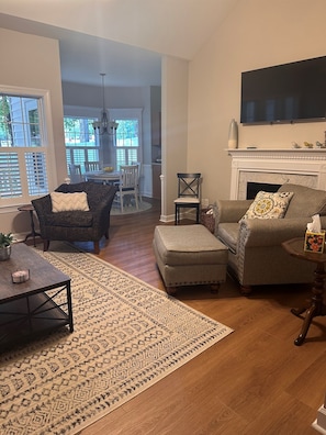 A living room with a sofa, ottoman, coffee table, and a fireplace.