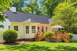 A two-story house with a covered patio, a wooden deck, and a brick foundation. - Private Wooded Retreat | Fenced Yard | Near Downtown (Wake Forest)