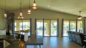 A spacious living area with a kitchen, large windows, and a ceiling fan. - Gorgeous 5-Star Home on the Lake, near Laughlin/Bullhead Casinos & Lake Mohave (Bullhead City)