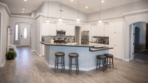 A modern kitchen with a central island, bar stools, pendant lighting, and built-in appliances. - Gorgeous 5-Star Home on the Lake, near Laughlin/Bullhead Casinos & Lake Mohave (Bullhead City)