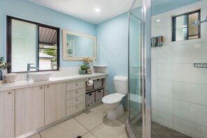 A modern bathroom with a large mirror, a white sink, and a glass shower enclosure.