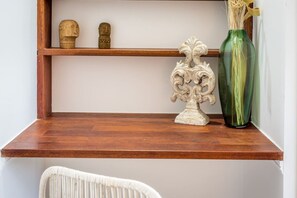 Une étagère en bois ornée d’objets décoratifs, notamment un vase et deux petites sculptures.