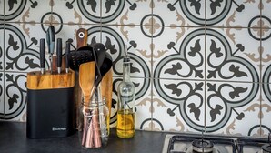 Une cuisine avec un crédence décorée, un range-couteaux, un pot à épices et une bouteille d’huile.