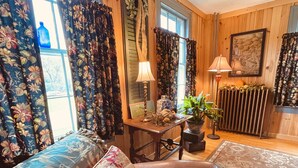 A cozy room with a sofa, a table with a lamp, a potted plant, and a radiator.