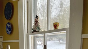 A wooden chair in a room with a window overlooking a snowy yard.