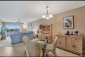 Relax in a spacious living area with a sofa, dining table, and wicker chairs, connected to a balcony with an outdoor view.