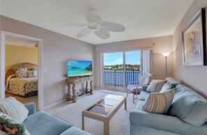 Relax in this spacious living room with a large flat-screen TV, ceiling fan, and stunning views of the water.