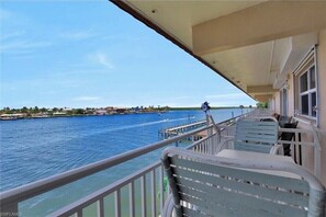 Enjoy serene views of the water from this balcony with a dock and boats in the distance.