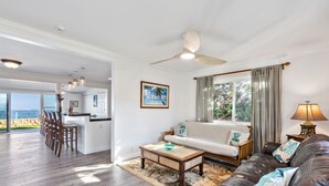 A spacious living area with a leather sofa, a coffee table, and a view of the ocean. - Oceanfront Mokuleia Home with Stunning Views (Waialua)