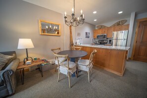 Cocina compacta con armarios de madera, una isla central y un comedor con mesa redonda y sillas.