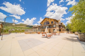 Relax in our spacious outdoor patio area with tables and chairs, surrounded by lush greenery and scenic hills.