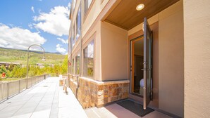 En hotellentrél med en fasad av sten, en glasdörr och utsikt över ett bergigt landskap.