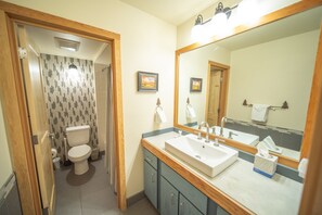 A bathroom with a toilet, sink, and mirror. - Pines 2167 (Keystone)