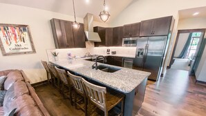 Una cocina moderna con armarios de madera oscura, encimera de granito y electrodomésticos de acero inoxidable.