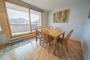 A dining area with a wooden table and chairs, large windows with a view of mountains, and a colorful abstract painting on the wall. - Argentine 1504 (Keystone)