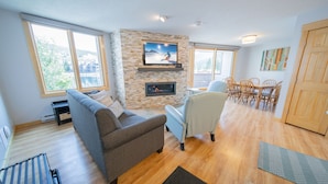 Una sala de estar moderna con chimenea, televisor y comedor con sillas de madera.
