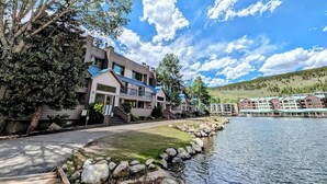 Un hotel a orillas del lago con varias construcciones, un camino de piedra y vistas al lago.
