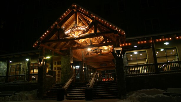 Een lodge met een houten gevel, een bord met daarop 'Buffalo Lodge' en een trap die naar de ingang leidt.