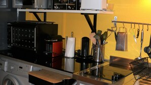 Une cuisine compacte équipée d’un lave-linge, d’un four à micro-ondes et d’un petit réfrigérateur.