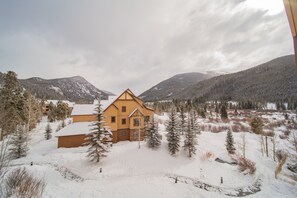 A large wooden house surrounded by snow-covered trees and mountains. - Red Hawk Lodge 2281 (Keystone)