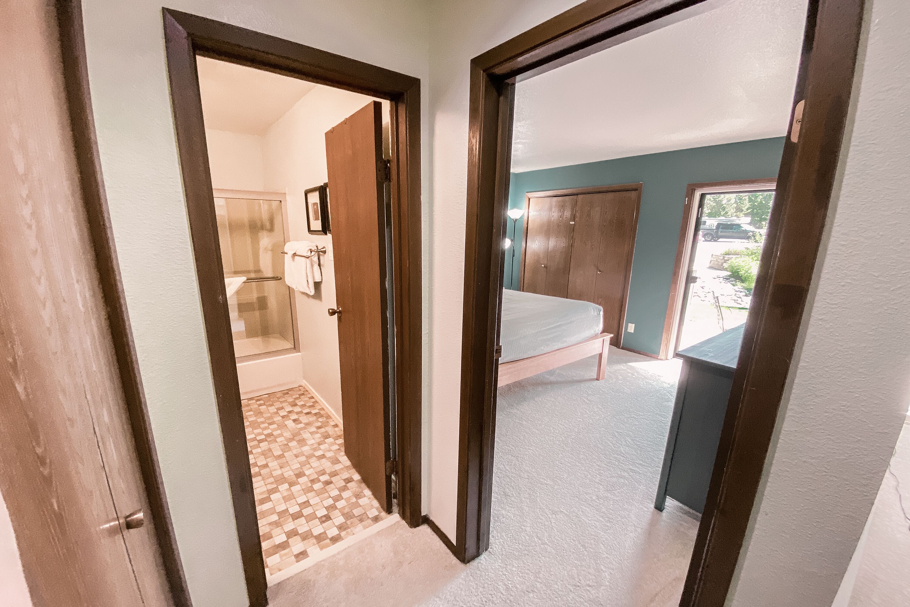 A hallway leading to a bedroom with a bed, a wardrobe, and a bathroom with a shower and toilet.