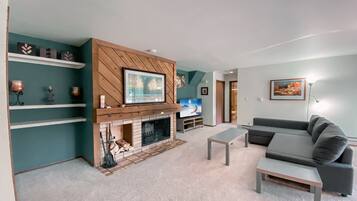 A modern living room with a fireplace, a grey sofa, and a flat-screen TV.