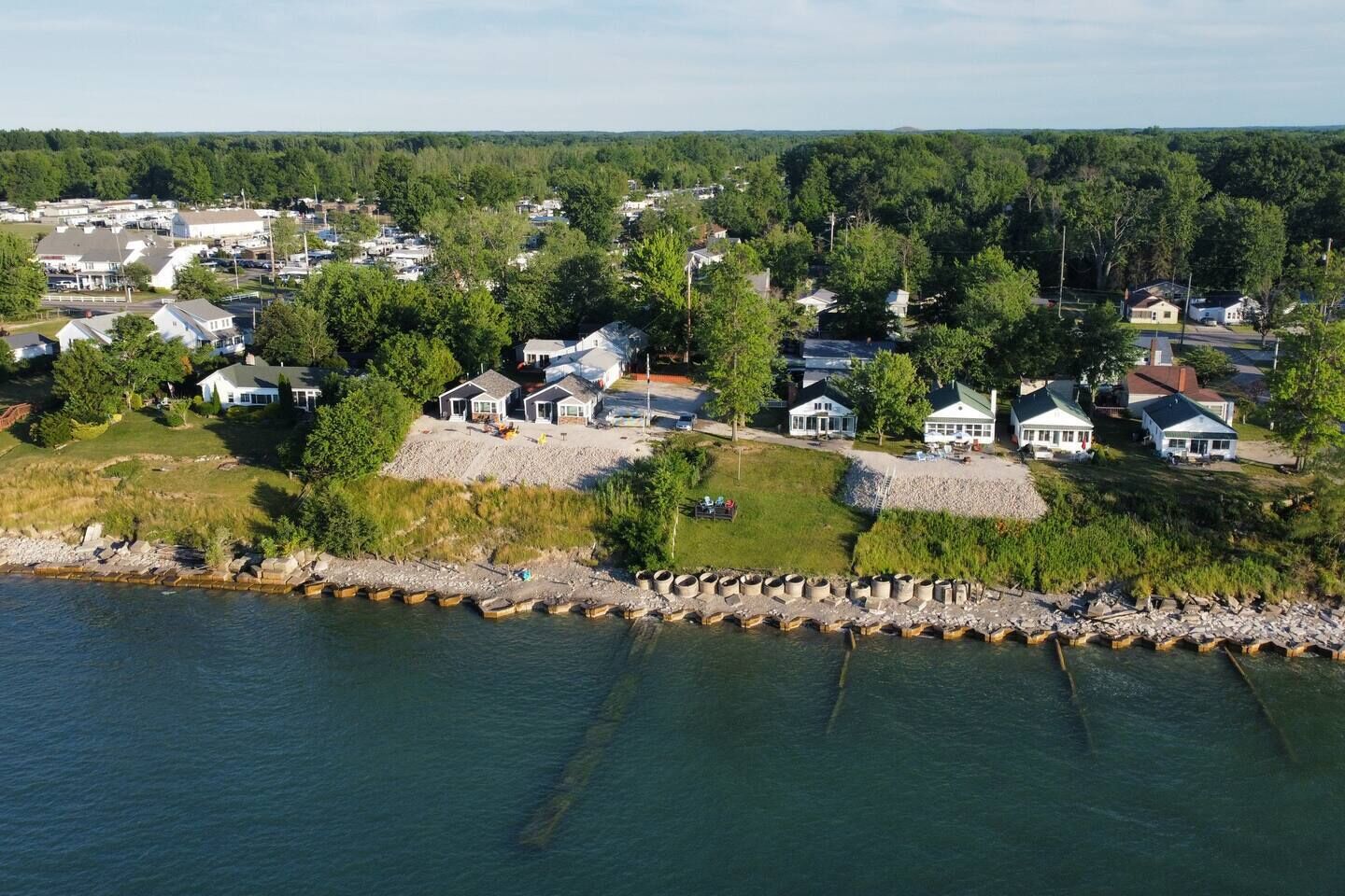 A residential area with houses near a body of water, featuring a dock and a rocky shoreline.