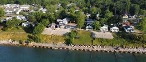 A residential area with houses near a body of water, featuring a dock and a rocky shoreline.