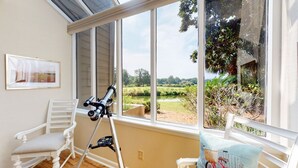 Ein Zimmer mit großem Fenster, einem Teleskop und einem Sessel.