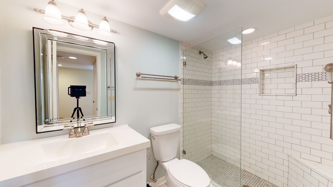 A modern bathroom with a white sink, a toilet, and a glass-enclosed shower area.