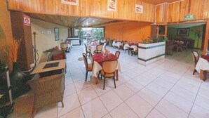 Ein Restaurant mit Holzwänden, Fliesenböden und mehreren Esstischen mit Stühlen.